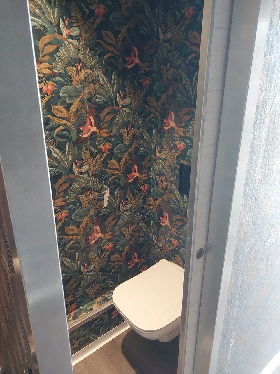 WC-Kabine mit dunkelgrüner Botanik-Tapete und Wand-WC