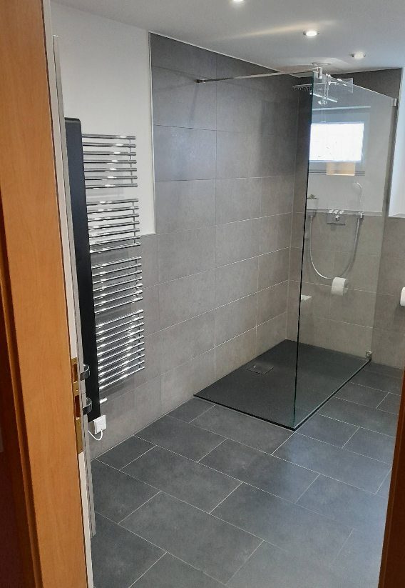 Bodengleiche Walk-in-Dusche mit Glaselement und Handtuchheizkörper