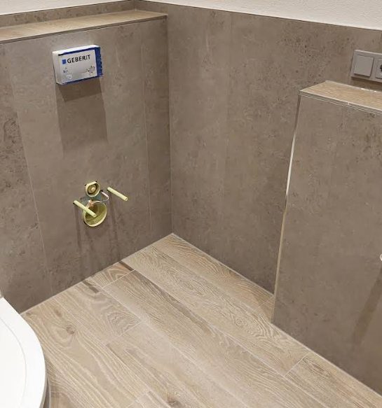 WC-Bereich mit Vorwandinstallation, großformatigen Wandfliesen und Boden in Holzoptik